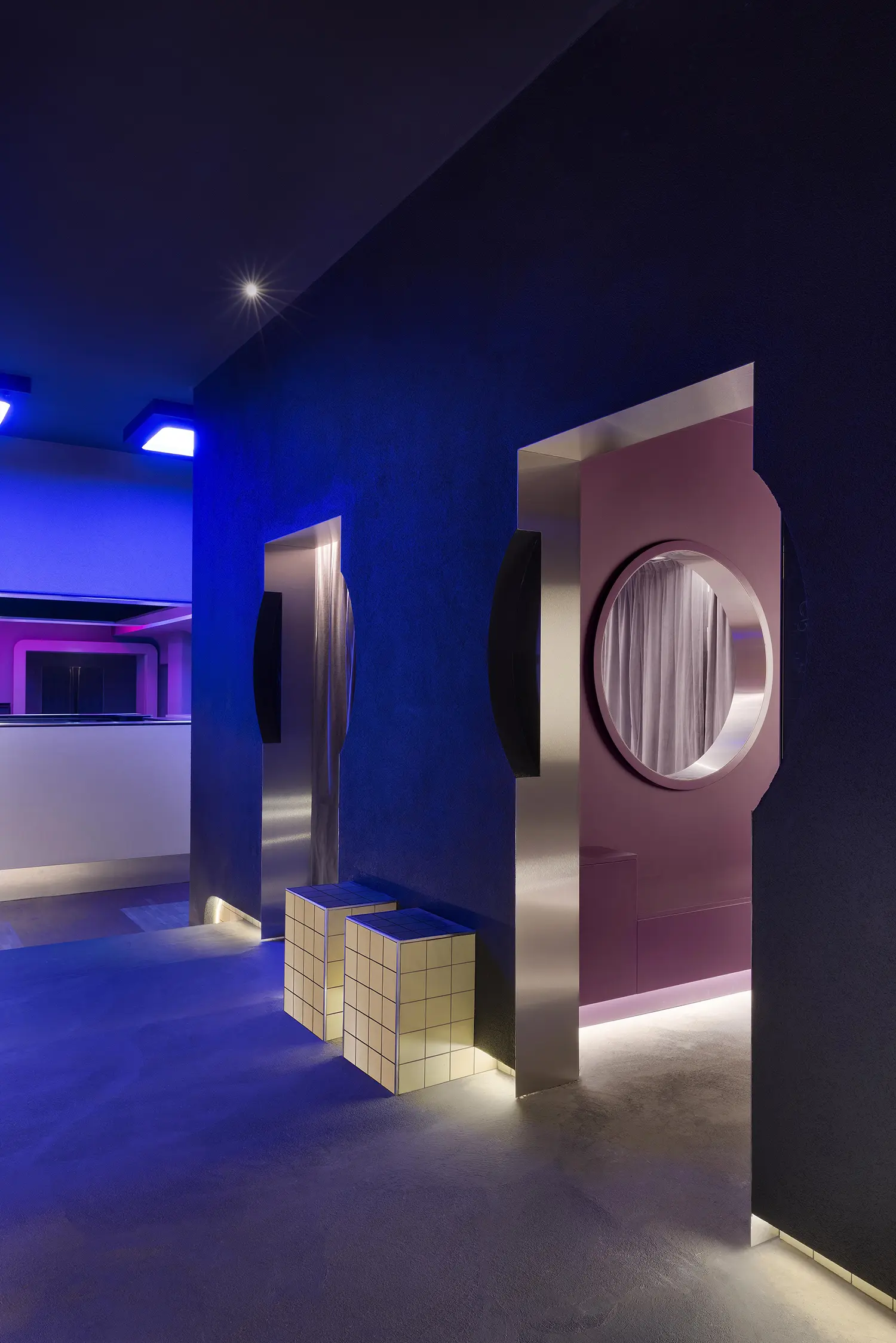 DURO club Milan Velvet Studio, blue lit interior with circular openings, tiled cube seating, steel-framed porthole passage