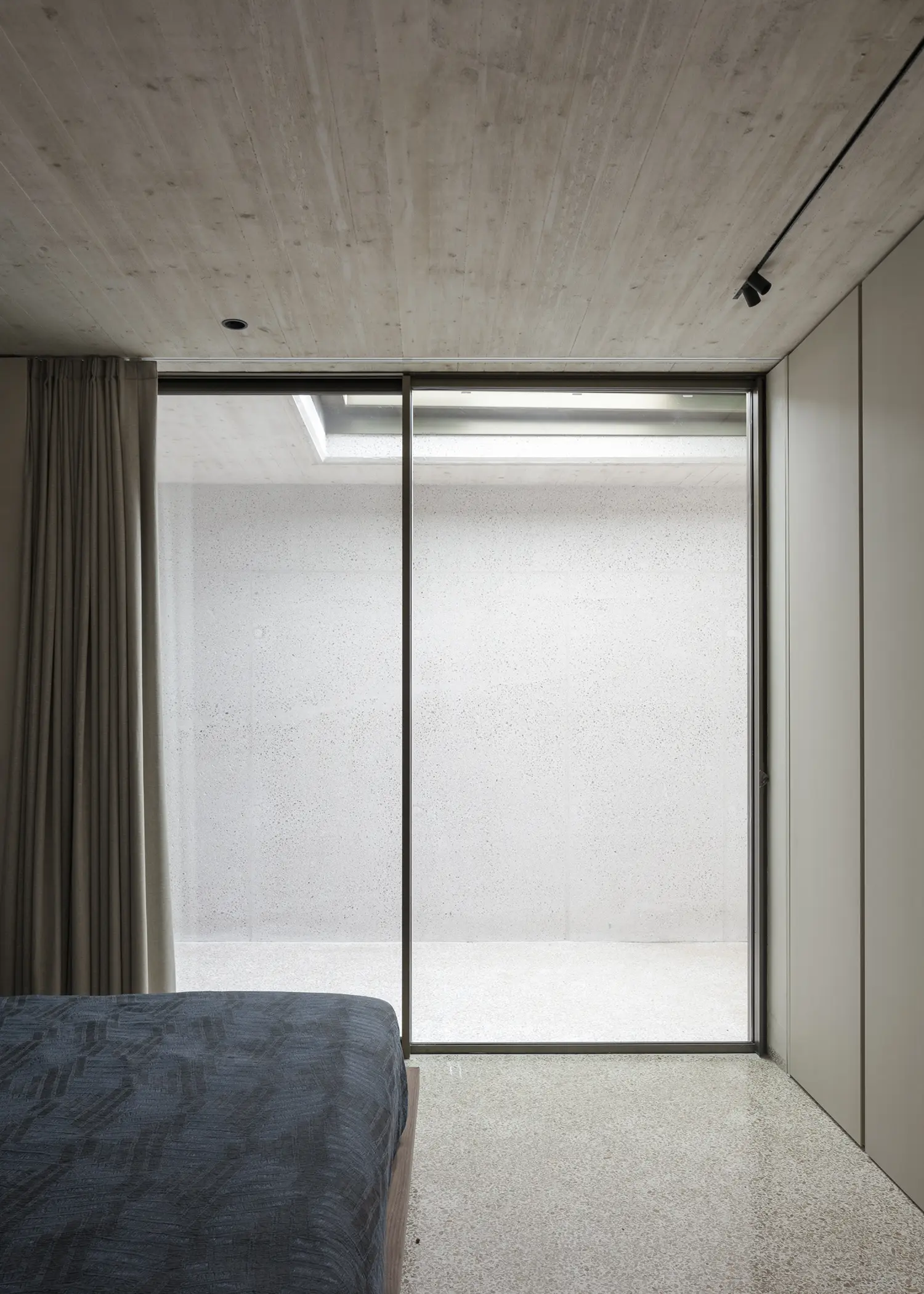 Villa S-2113 Calvi Ceschia Viganò, bedroom with full-height glazing onto concrete courtyard, board-formed ceiling, Genoese terrazzo