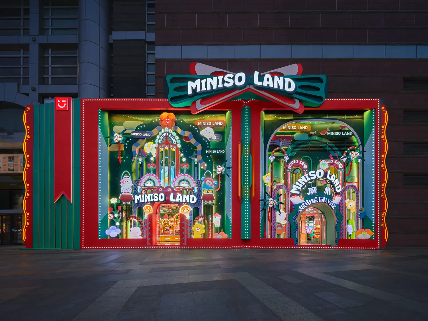 Three-dimensional pop-up style facade of MINISO LAND Guangzhou flagship store at night with bright neon lights.