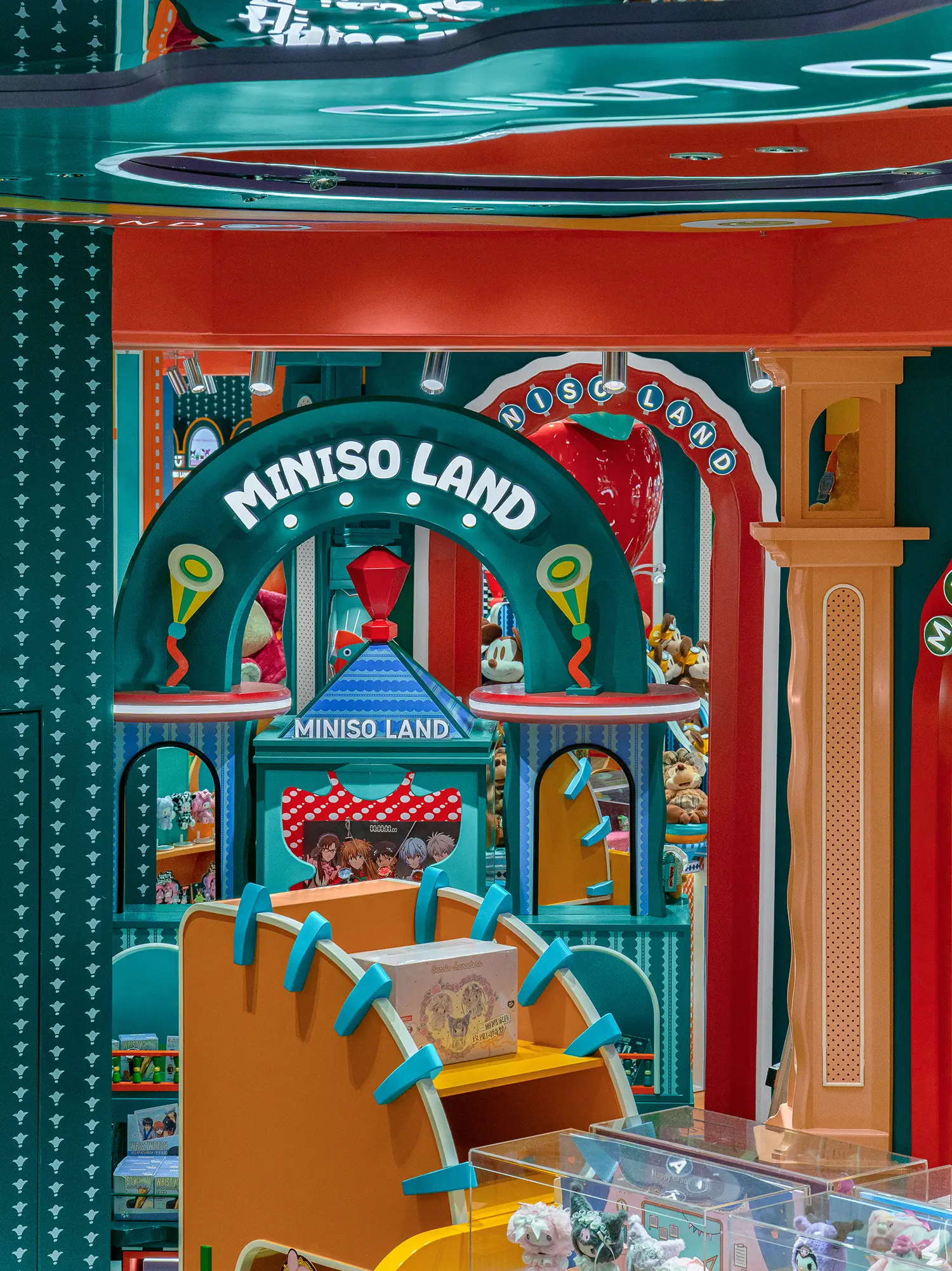Close-up of layered green and orange architectural display structures inside MINISO LAND Guangzhou.