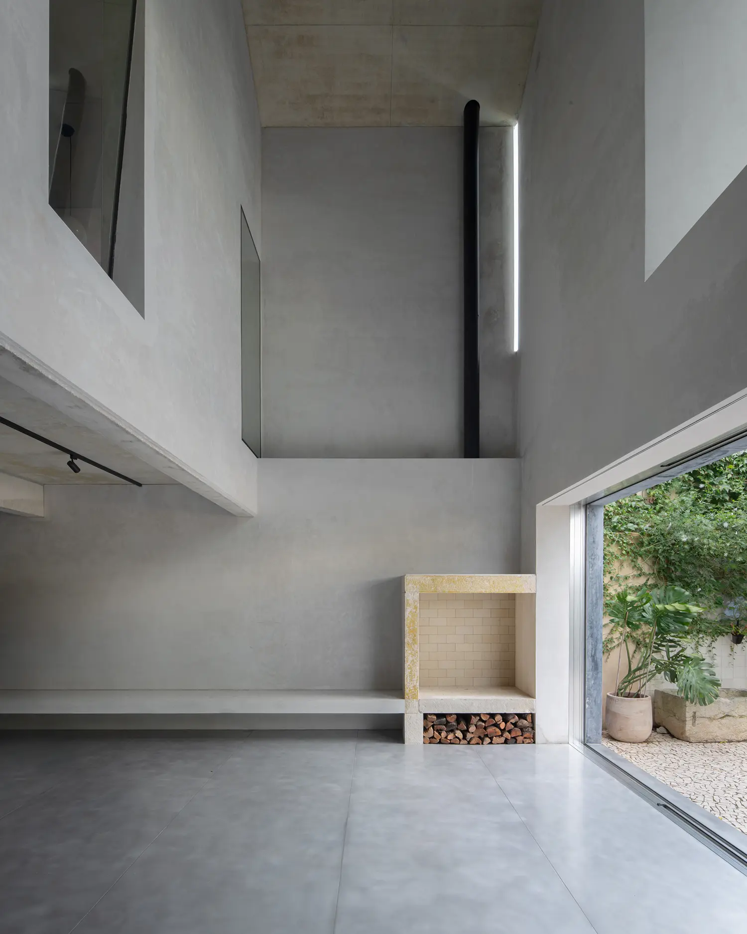 Blue House extrastudio Marvila Lisbon triple height interior grey scratch coat plaster aluminium floor fireplace light slit