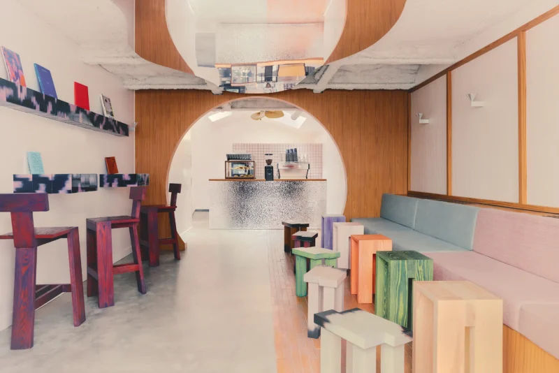 Café Shin Marais Uchronia Paris main room arch hammered chrome counter multicolor wood stools bench seating oak paneling