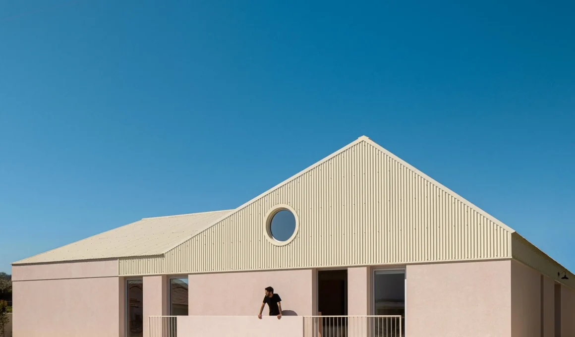 Casa do Alpendre Vasco Burnay Arquitectura pink render facade pitched metal roof circular window Vila Franca de Xira