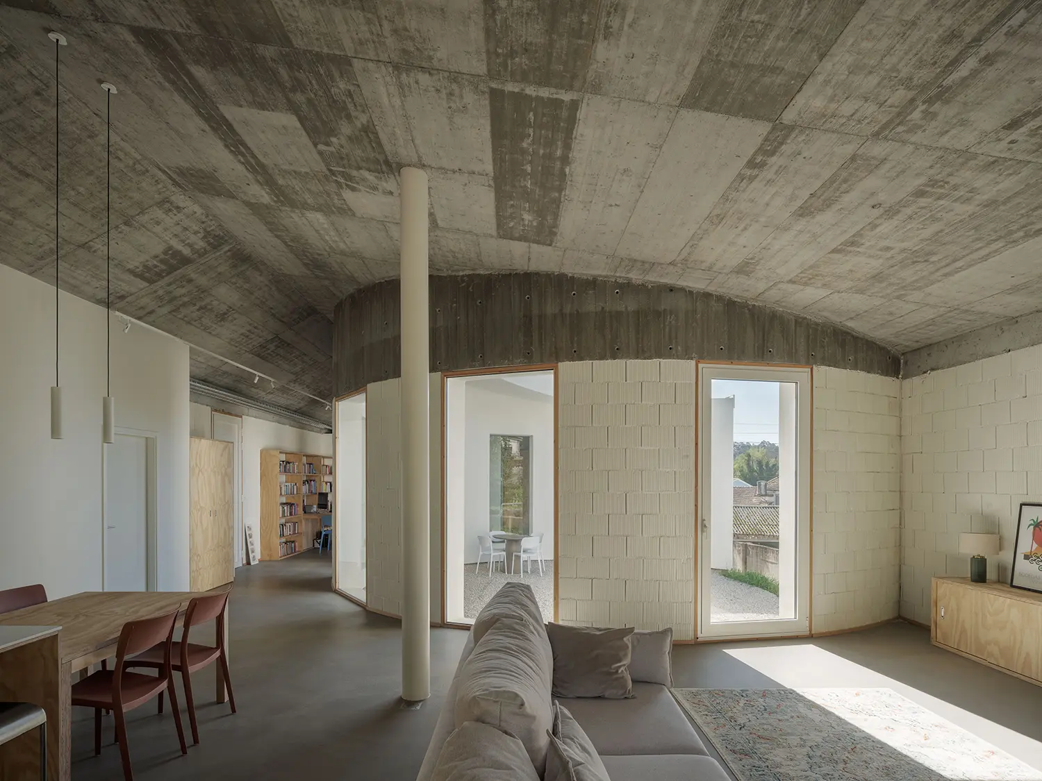 Cecebre House Sinaldaba Galicia living room exposed concrete ceiling cellular concrete block walls plywood joinery courtyard view