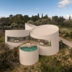 House in Las Rozas by Fran Silvestre Arquitectos, aerial view of five cylindrical volumes on hillside with pool