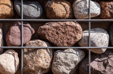Close-up detail of gabion cage filled with multicoloured natural stone, wire mesh grid visible