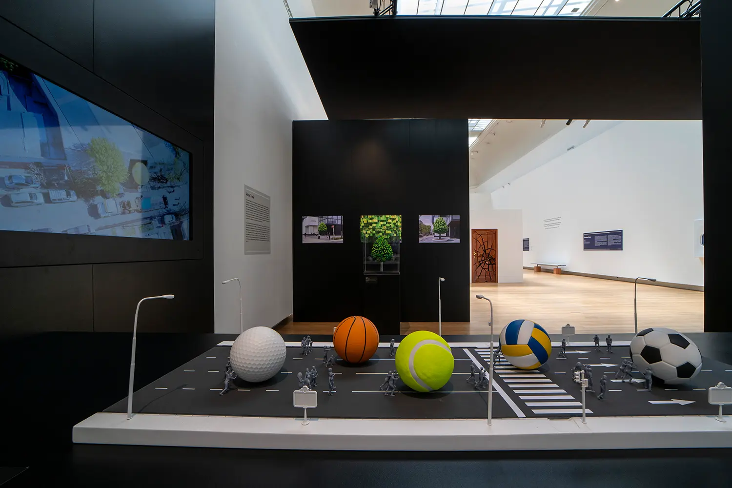 Leandro Erlich scale model installation Grand Palais Paris, miniature city street with oversized sports balls disrupting urban scale, display wall