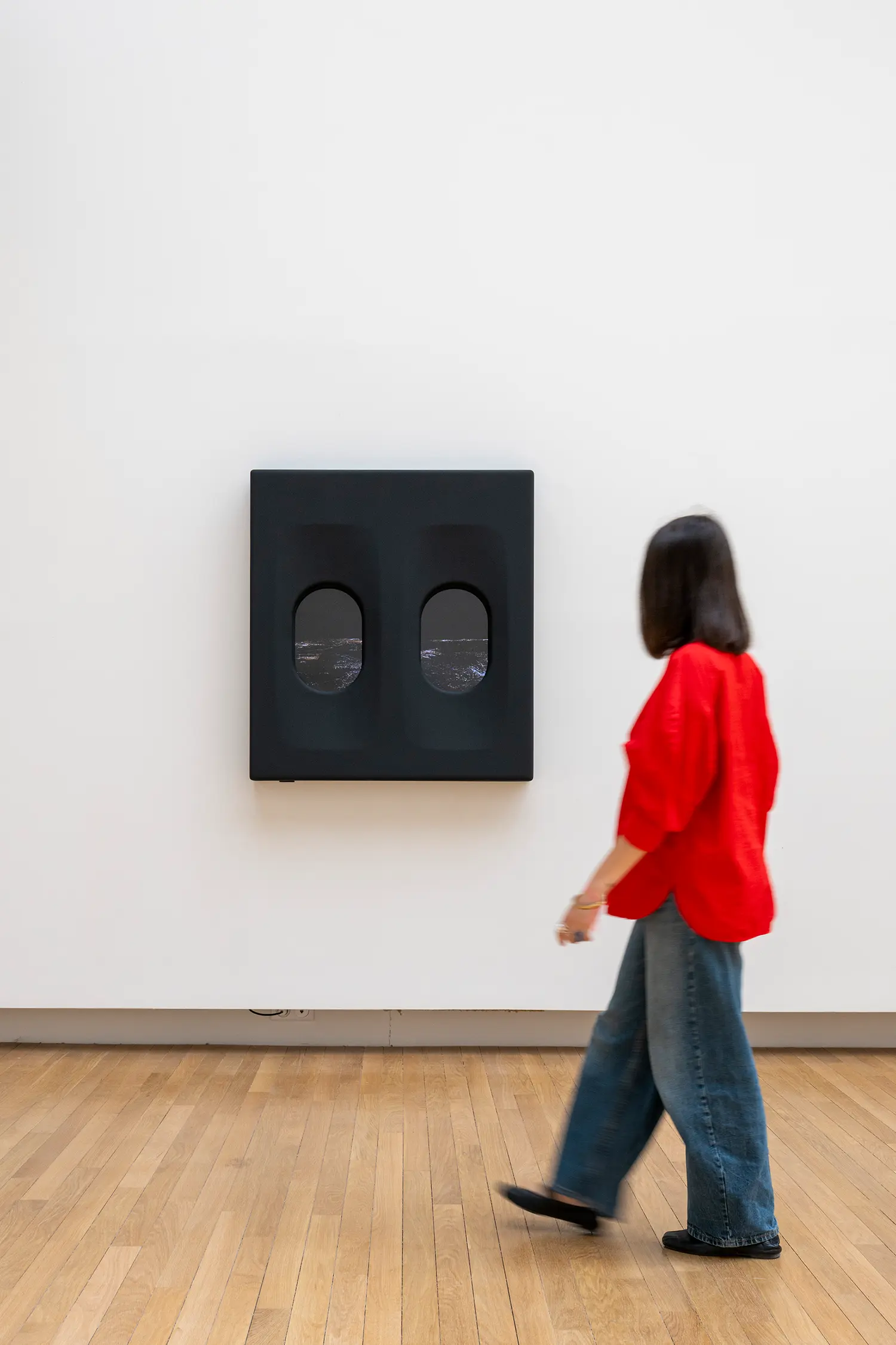 Leandro Erlich airplane window installation Grand Palais Paris, dark panel with two oval portholes showing nighttime aerial view, visitor in motion