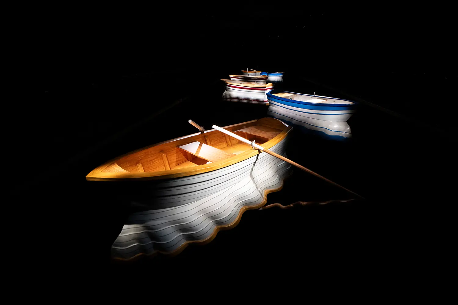 Leandro Erlich Port of Reflections Grand Palais Paris, three fiberglass rowboats illuminated on dark floor, motor-animated hulls, no water surface