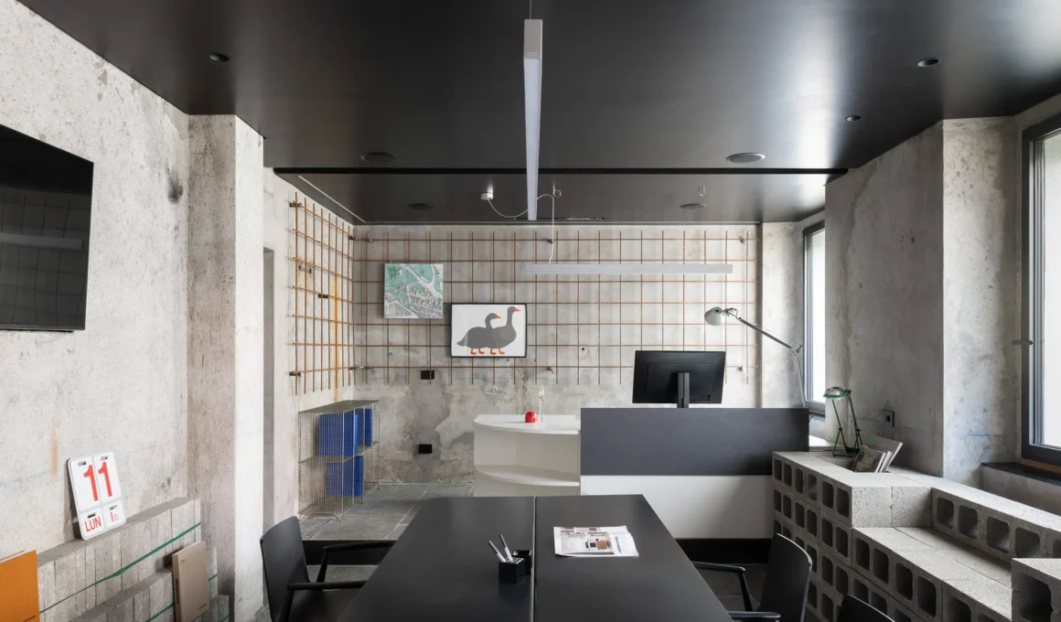 RAW Studio Moroni Architettura Sondrio raw plaster walls oxidized welded mesh display grid black ceiling iron table