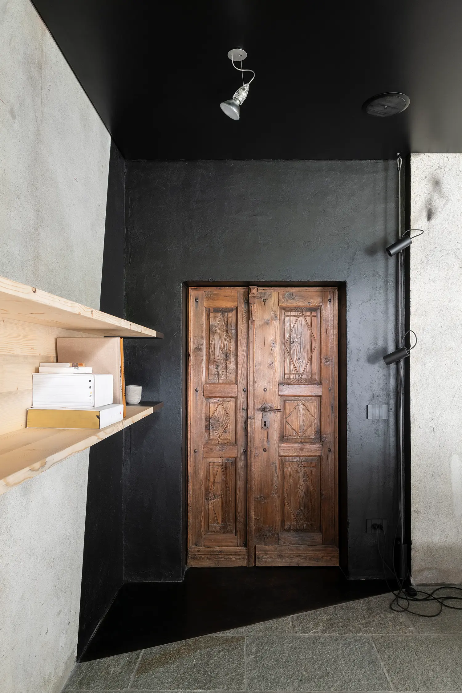 RAW Studio Moroni Architettura Sondrio black diagonal wall antique solid wood door pine shelving stone floor