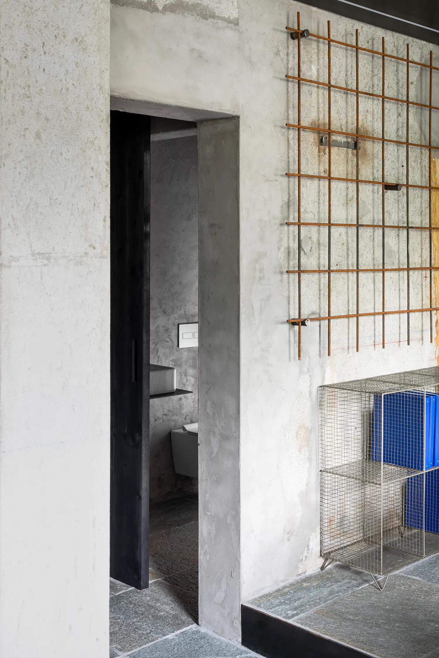 RAW Studio Moroni Architettura Sondrio oxidized welded mesh display wall raw plaster bathroom doorway stone floor
