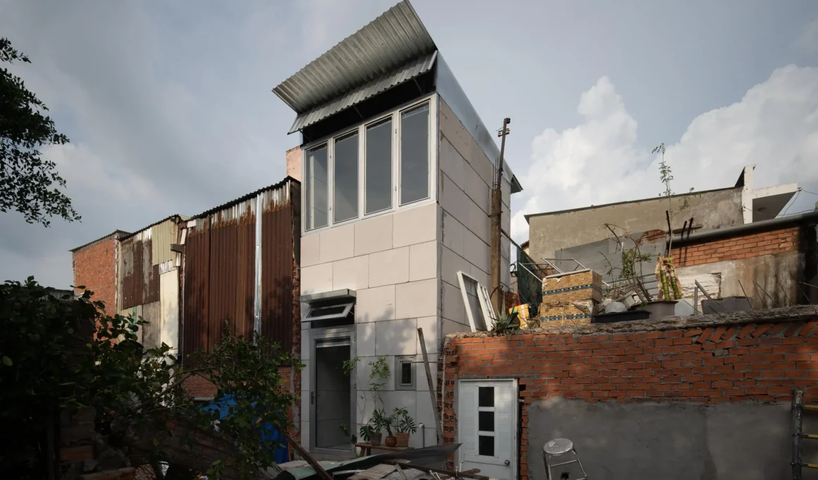 11M2 House by SCALE 50, AAC panel white volume rising above brick walls and corrugated metal structures, Ho Chi Minh City canal