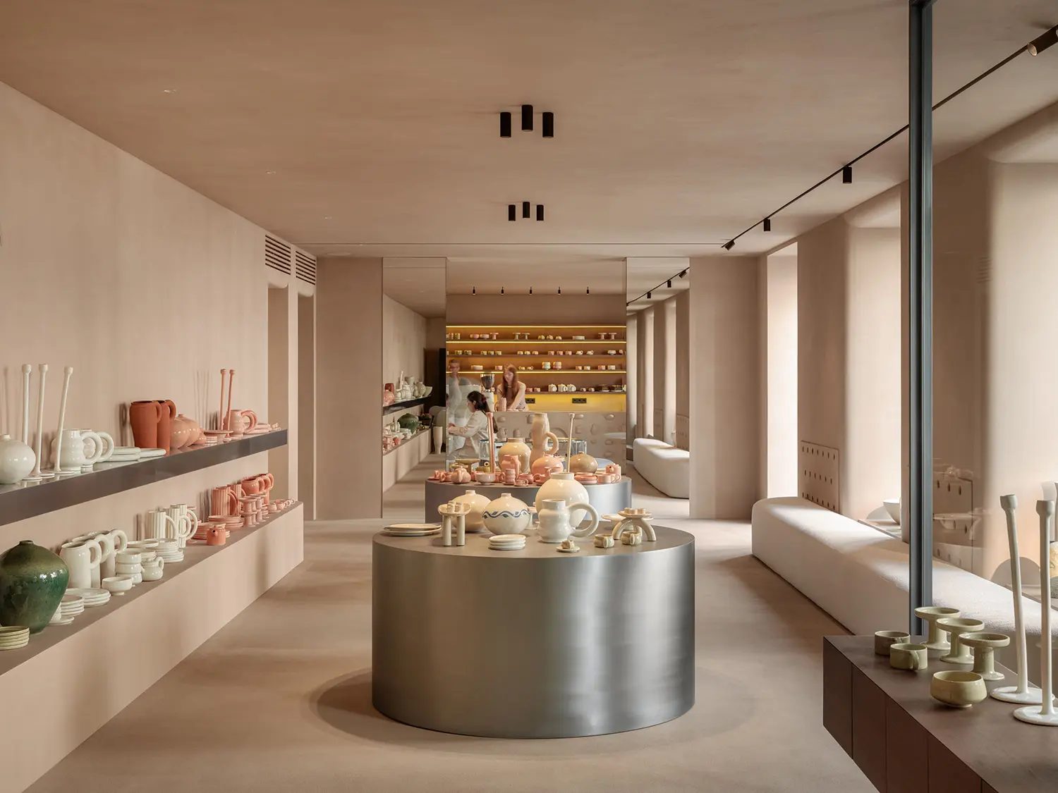 SHOLOMITSKA ceramics store Kyiv interior, full-length view through rounded openings, mirrored arch threshold, steel display plinths, warm tone walls floor and ceiling