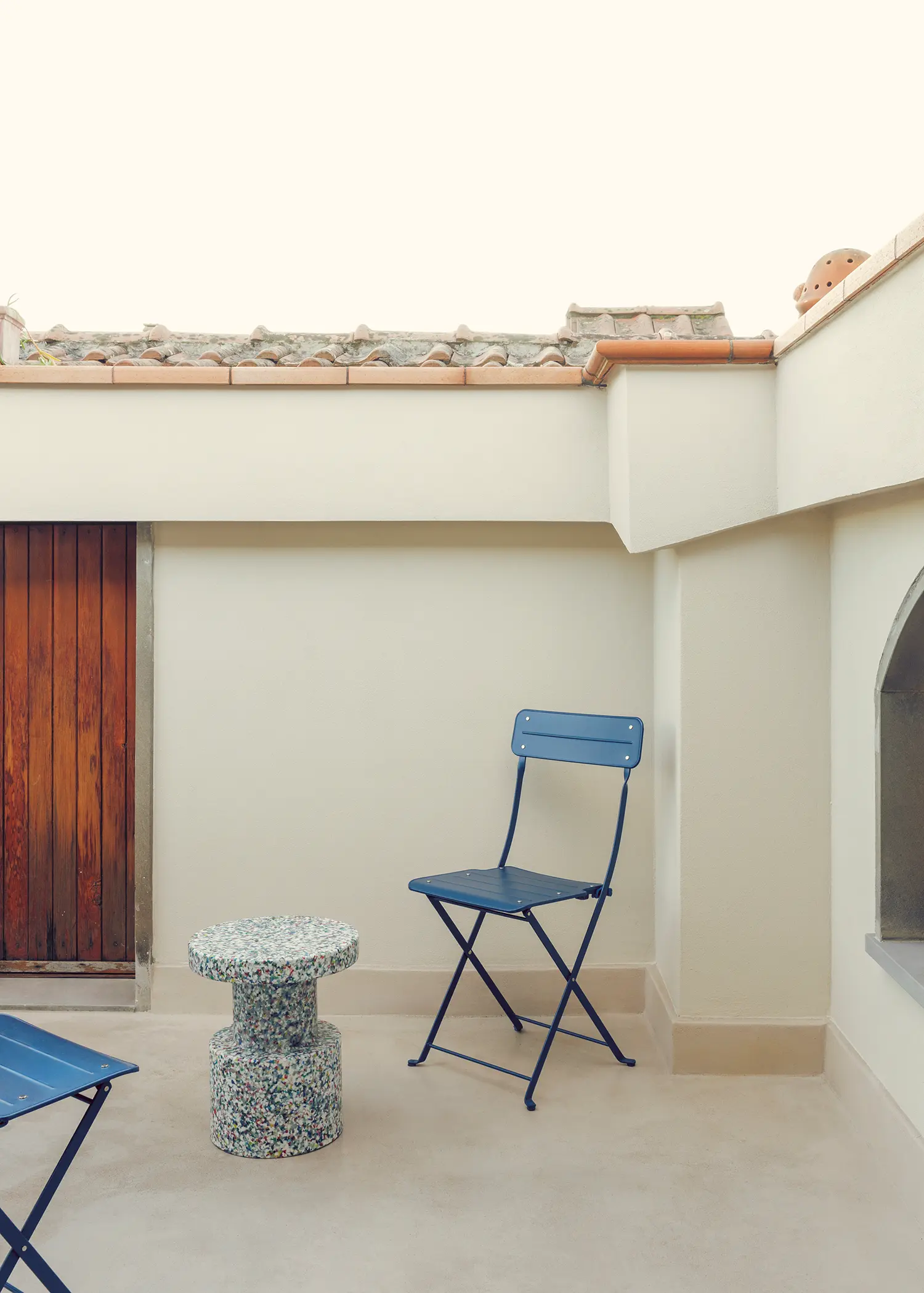 The Lobster bucci quentin, pocket terrace with recycled terrazzo stool, blue folding chair, Tuscan terracotta roof tiles, Prato 2026