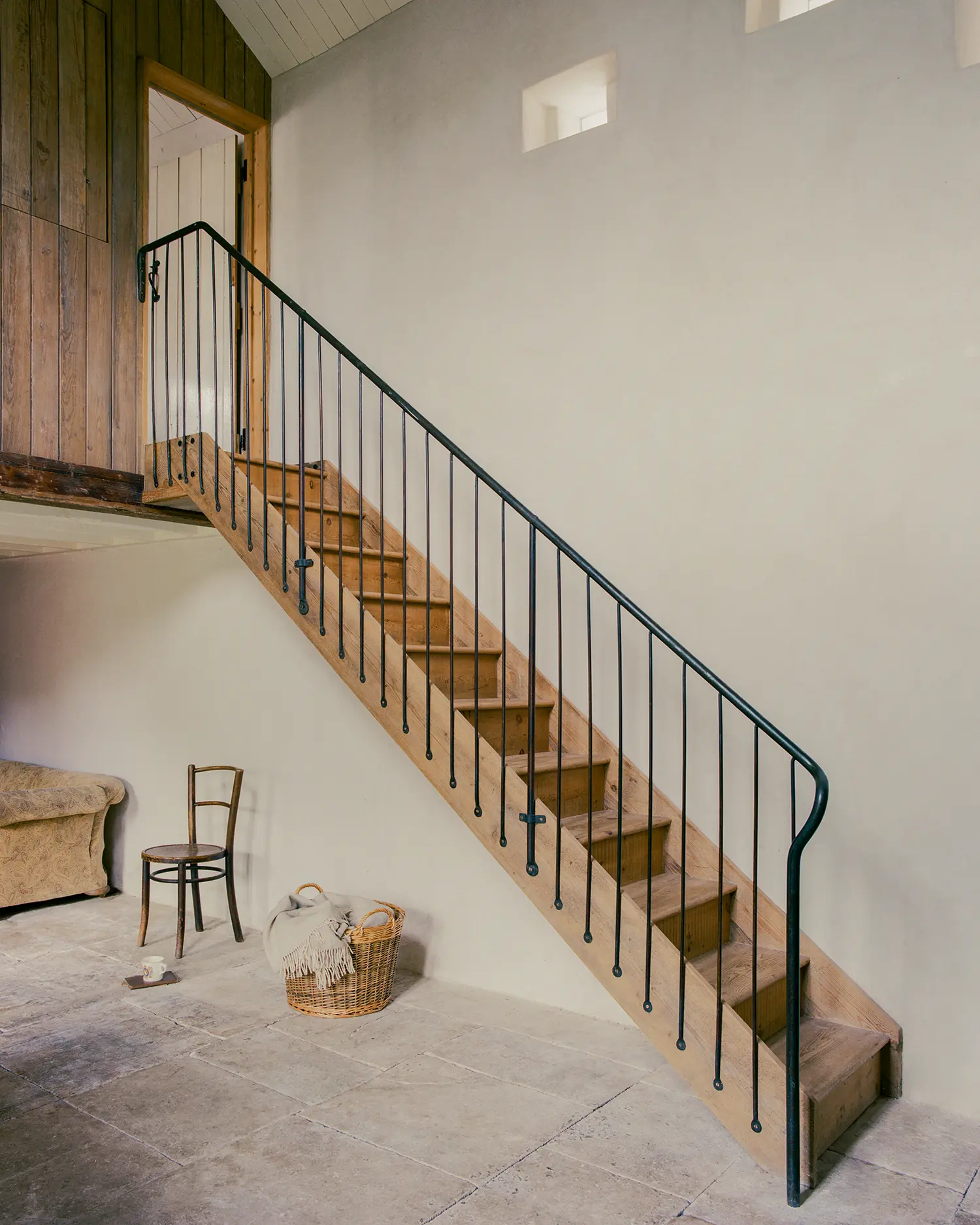 Reclaimed timber staircase at Purbeck Cottage by TYPE, hand-forged steel balustrade against lime-plastered wall leading to mezzanine writer's room