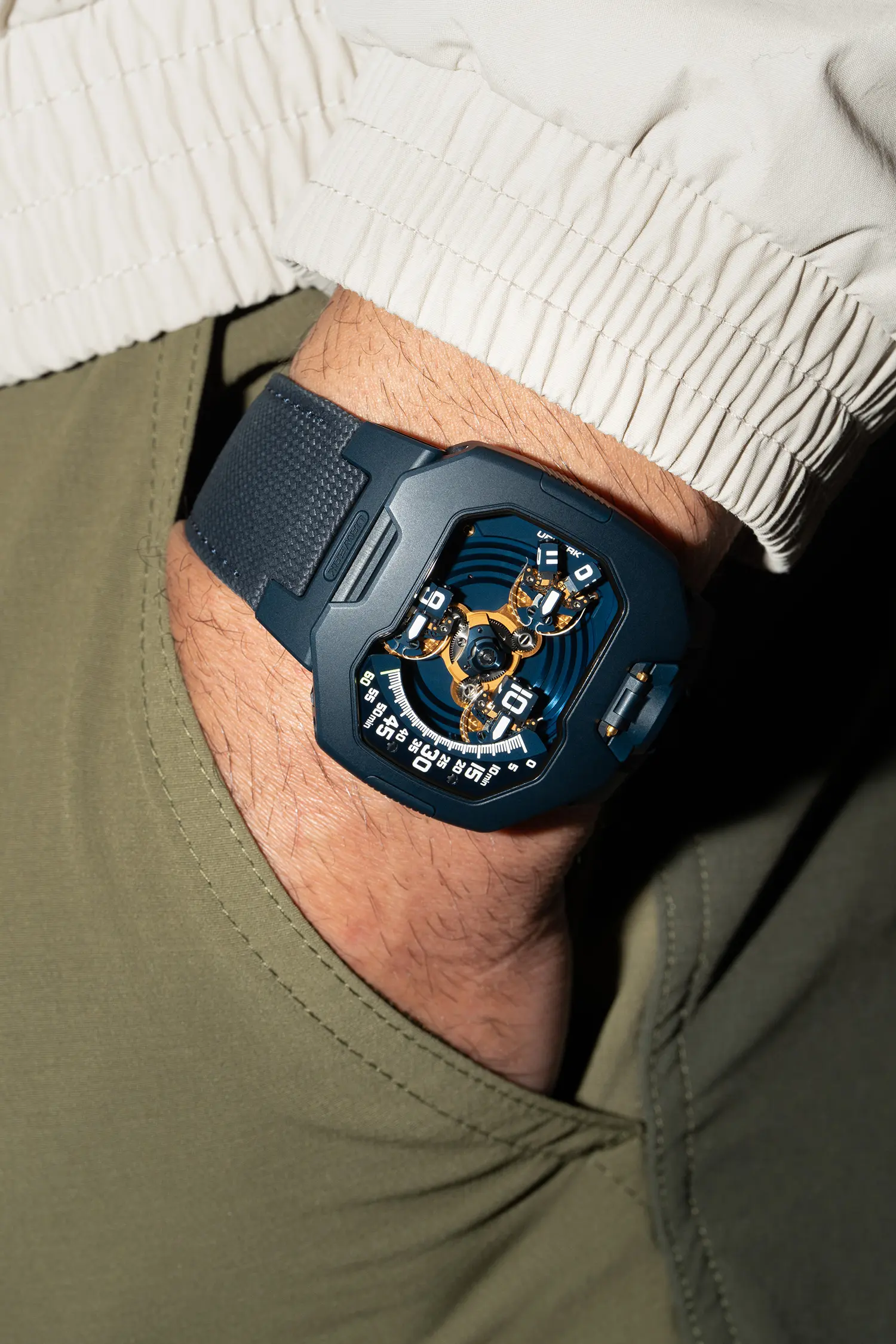 URWERK UR-120 Blue Planet on wrist, hand in trouser pocket, gold PVD satellite carousel display, sandblasted blue steel case, lifestyle shot