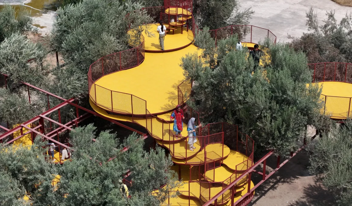 Cheshm Cheran Bazi playground ZAV Architects, yellow perforated platforms and red steel frames threading through olive orchard canopy, aerial view, Minoudasht Iran