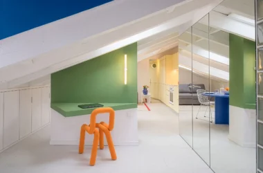 Attic apartment at night by gon architects, orange sculptural chair, mirrored wall reflecting living room beyond