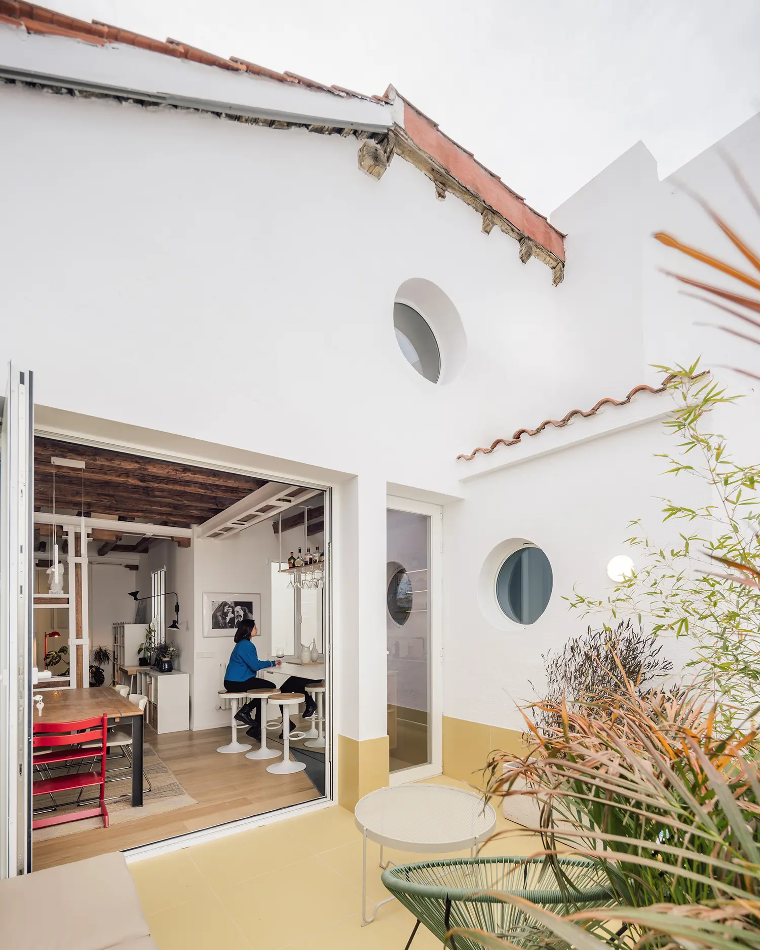 Exterior facade of Madrid attic renovation showing round porthole windows cut into white rendered wall