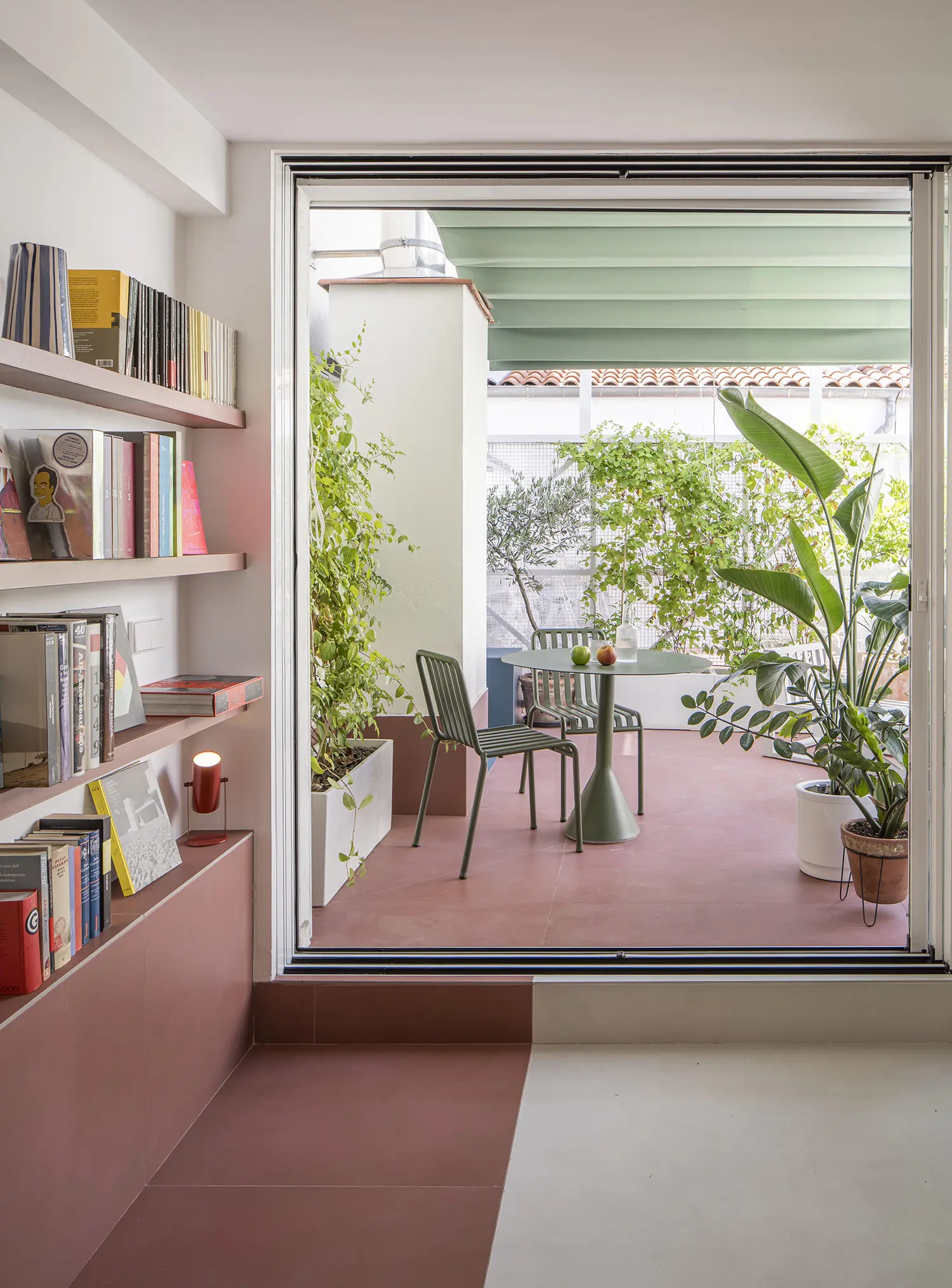 Attic apartment with terracotta tiled terrace, sliding glass door, potted plants, book-lined interior wall