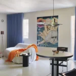 Macedonia apartment by Bardo, Madrid — living and dining area with neon acrylic threshold, blue curtains, and vintage artwork