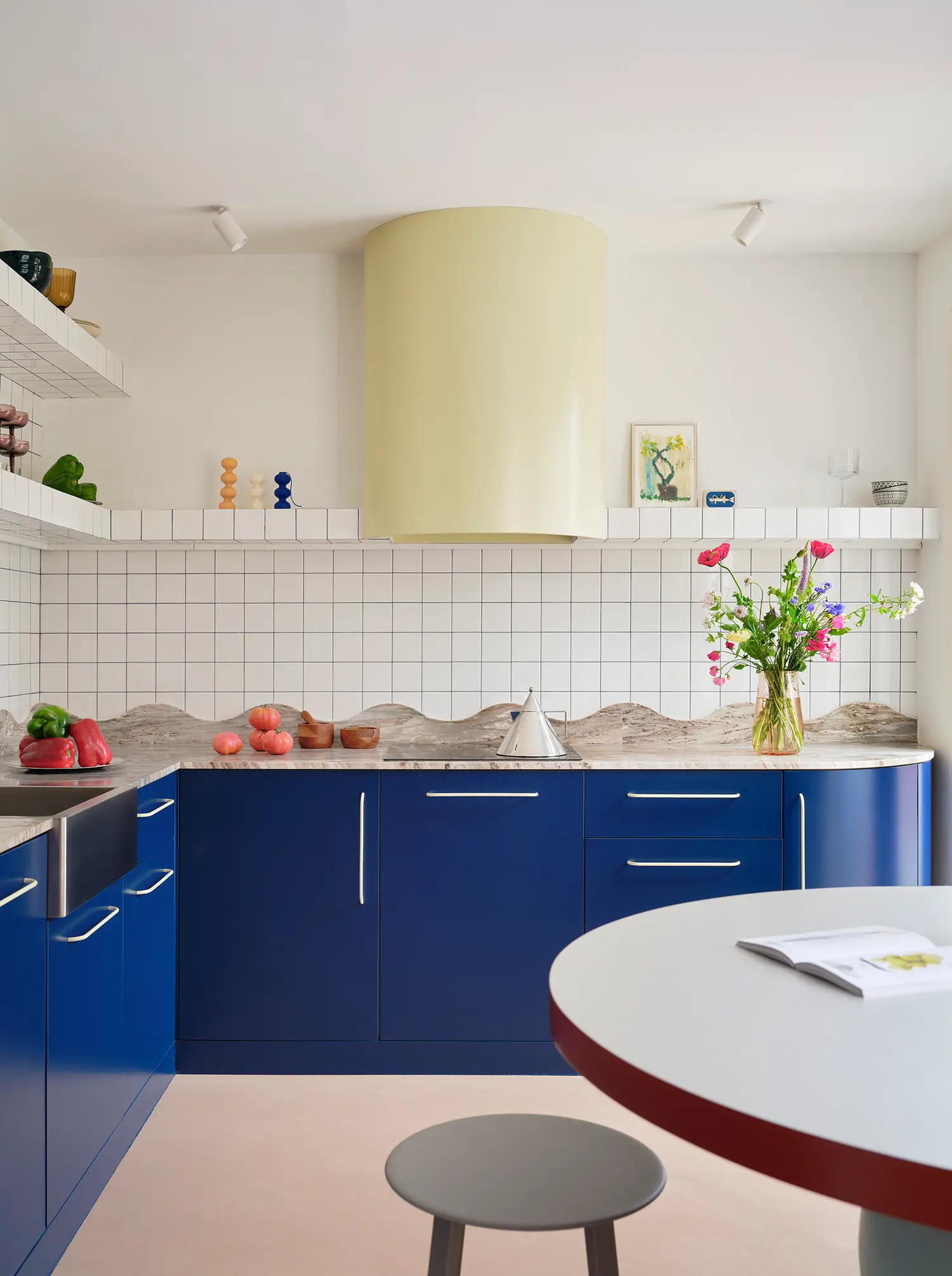 Macedonia by Bardo, kitchen with deep blue cabinetry, white tile, and undulating stone countertop