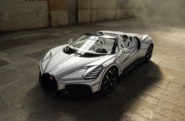 Bugatti W16 Mistral 'Blanc Éternel' roadster, front three-quarter elevated view, white bodywork with black line graphic, industrial warehouse interior