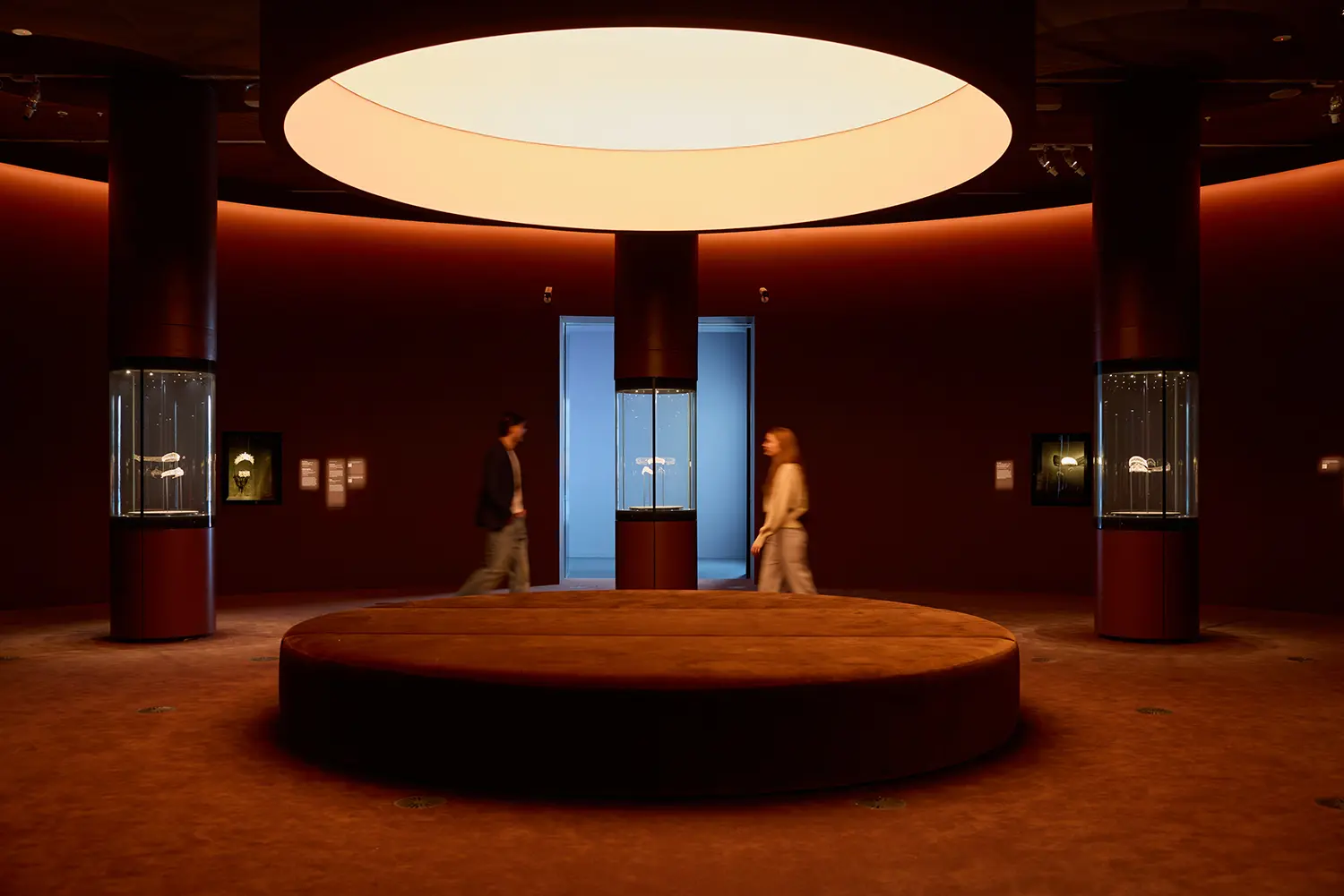 CARTIER exhibition at NGV Melbourne: deep burgundy circular gallery with oval ceiling light, tiaras in glass cases and central velvet ottoman