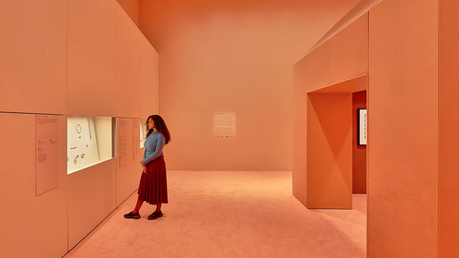 CARTIER exhibition at NGV Melbourne, Studio Sabine Marcelis design: monochromatic salmon gallery with wall-embedded display cases and chamfered archway