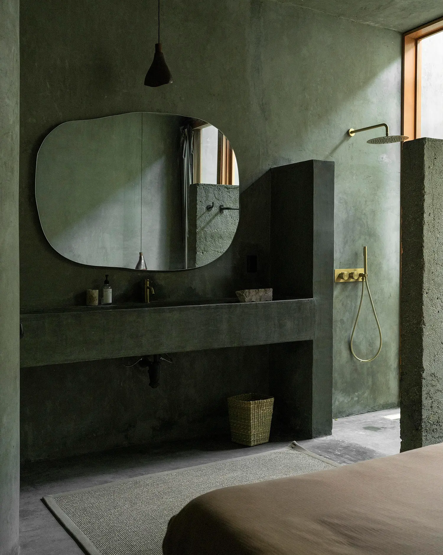 Casa Gruta concrete bathroom with organic-shaped mirror and brass fixtures, Salvador Román & Adela Mortera