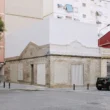 Casa Nido by Iterare Arquitectos, corner exterior in Torrefiel with preserved brick base and new white upper volume above ornate stucco cornice
