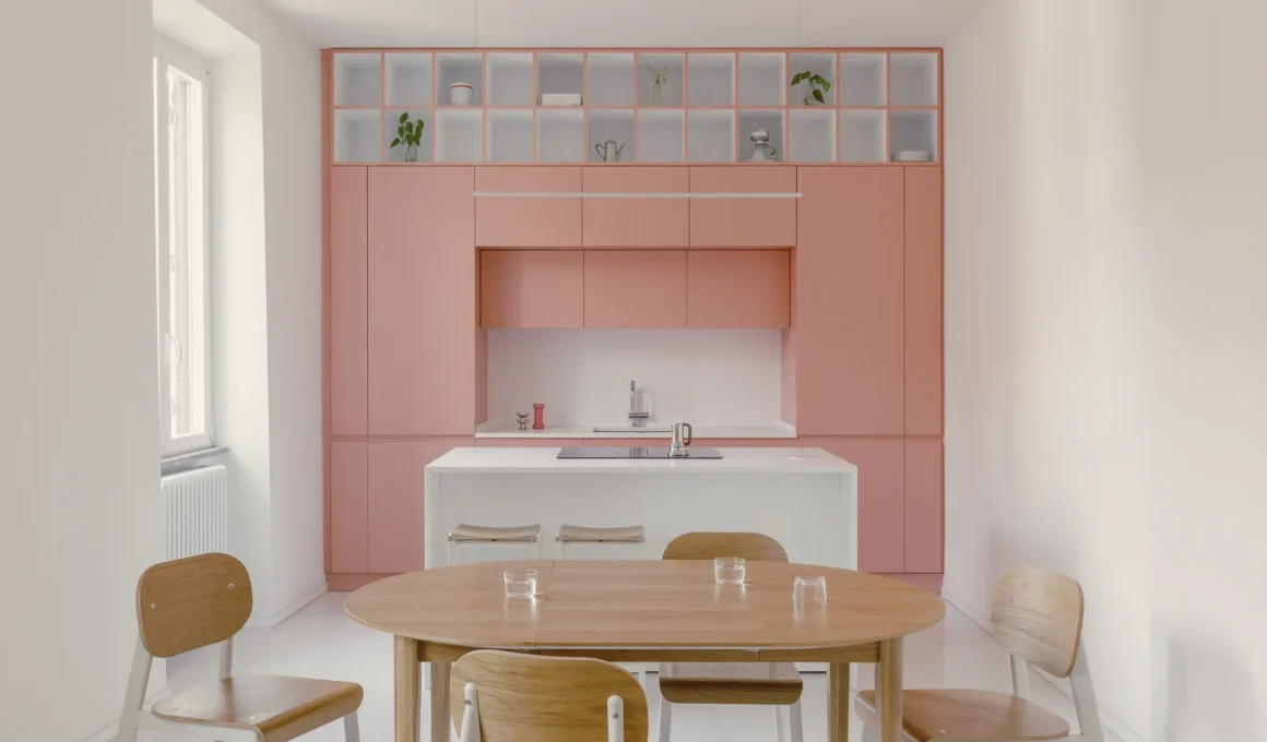 Casa Tahiti by Margine, pink kitchen and dining area, white Krion island, oak table, Arabescato terrazzo flooring