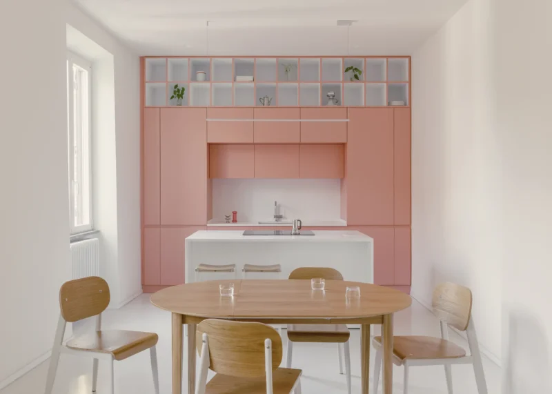 Casa Tahiti by Margine, pink kitchen and dining area, white Krion island, oak table, Arabescato terrazzo flooring