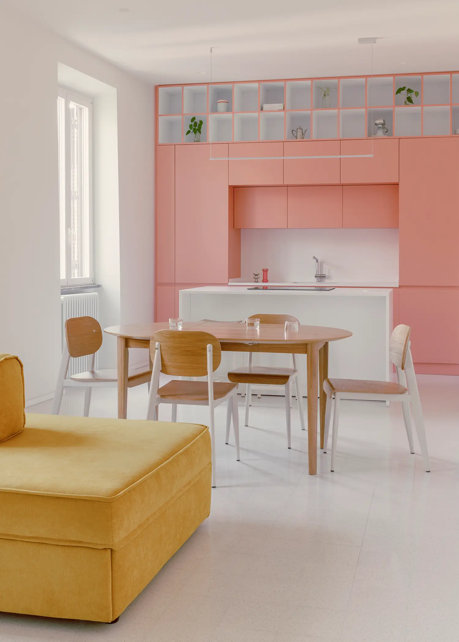 Casa Tahiti by Margine, living area with ochre-yellow sofa, pink kitchen and dining table beyond