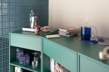 Container 03 by Atelierzero: sage-green kitchen counter against a perforated teal concrete-block wall, with moka pot and glassware