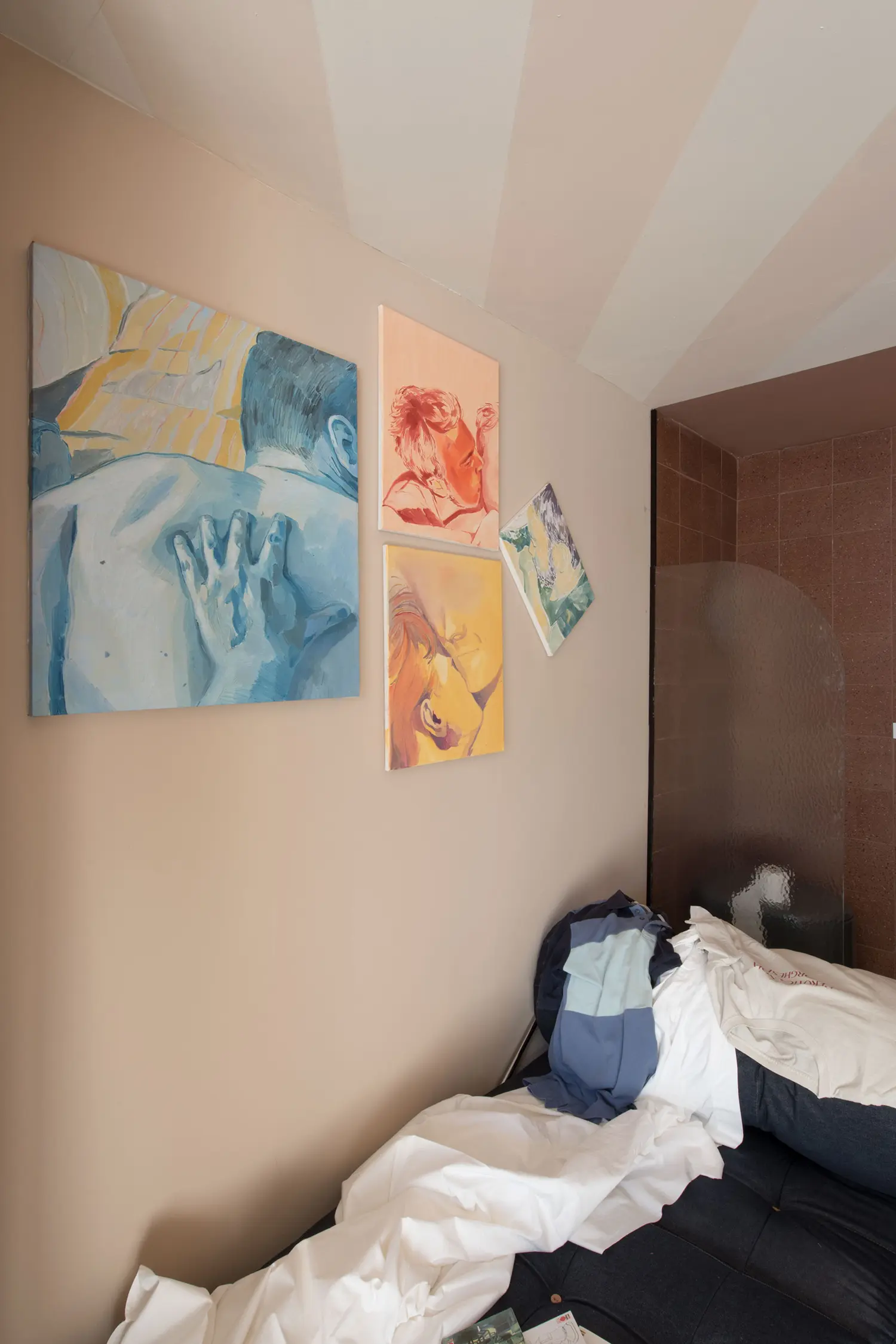 Container 03 installation, Atelierzero: figurative paintings by Nicolò Bruno above an unmade bed with backpack and clothing