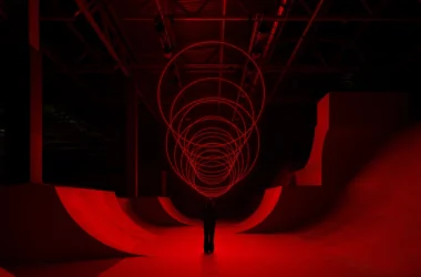 SpY's CYCLES N2 kinetic installation with red-lit rings suspended above a viewer in a ramp-lined hall in Kazan