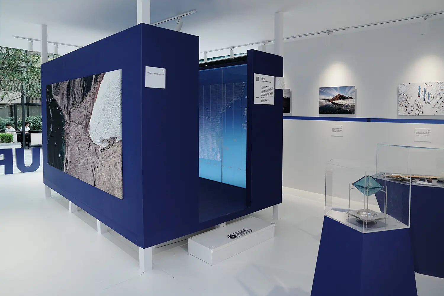 Deep-blue display volume in Resonance of the Extremes by Dayuan Design with a glacier photograph and a liuli glacial object in a vitrine