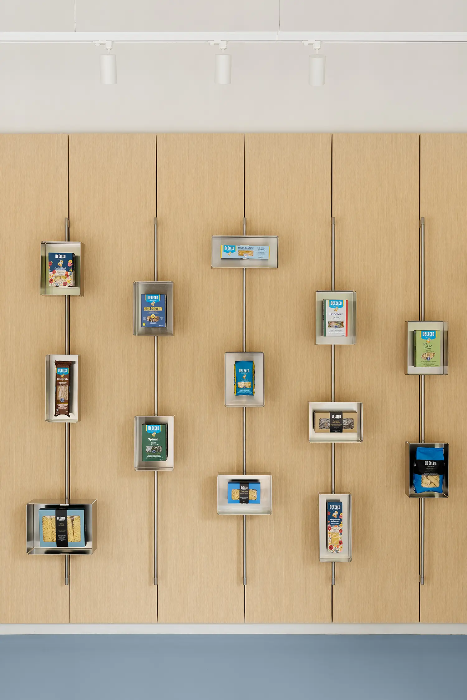 De Cecco Flagship Store by Studio Francesco Faccin, close-up of steel display frames on timber wall, individual pasta packages mounted vertically
