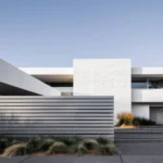 Modern white house with horizontal slat fence matching the garage door's linear pattern and desert landscaping