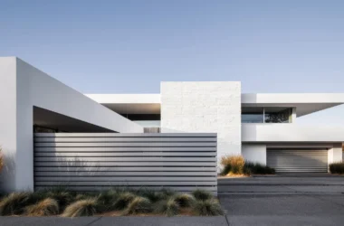 Modern white house with horizontal slat fence matching the garage door's linear pattern and desert landscaping