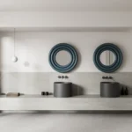 Double-sink bathroom vanity with matching cylindrical basins, wavy blue-framed round mirrors, and a light stone countertop