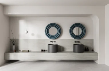 Double-sink bathroom vanity with matching cylindrical basins, wavy blue-framed round mirrors, and a light stone countertop