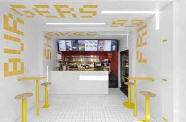 Interior of Fab Fries Freddy by Ninetynine, Amsterdam, showing white tile walls and ceiling narrowing toward a red-tiled prep counter