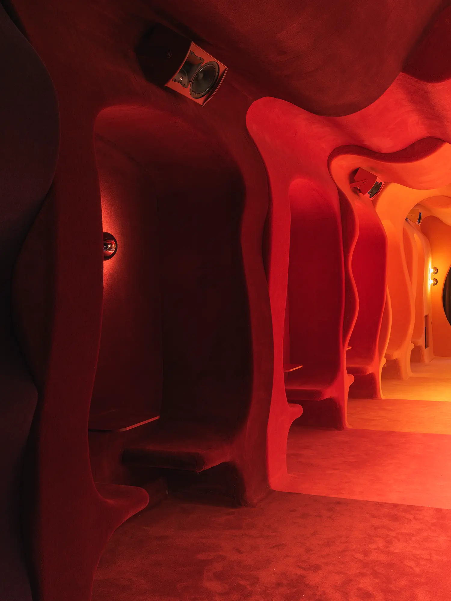 Detail of red carpeted booth niches in Focacha by Isern Serra, organic sculpted forms with integrated speaker and wall sconce