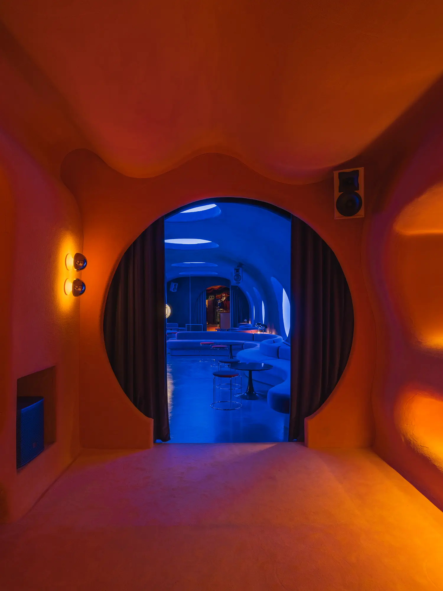 Circular doorway inside Focacha by Isern Serra, framing the transition from the orange bar room into the blue DJ room beyond