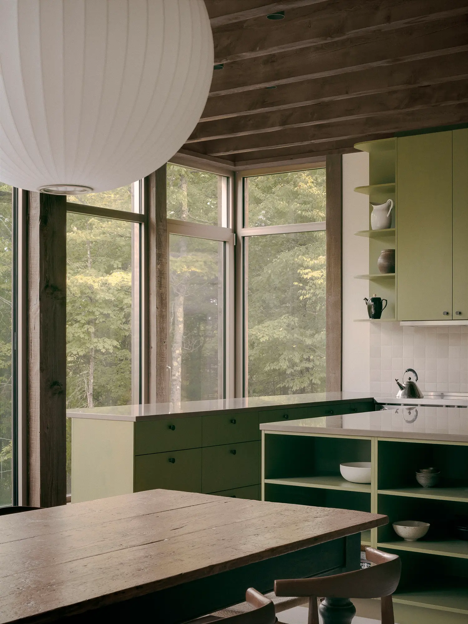SONO Residence kitchen detail by Atelier Carle — open shelving, ceramic bowls, corner window onto forest canopy