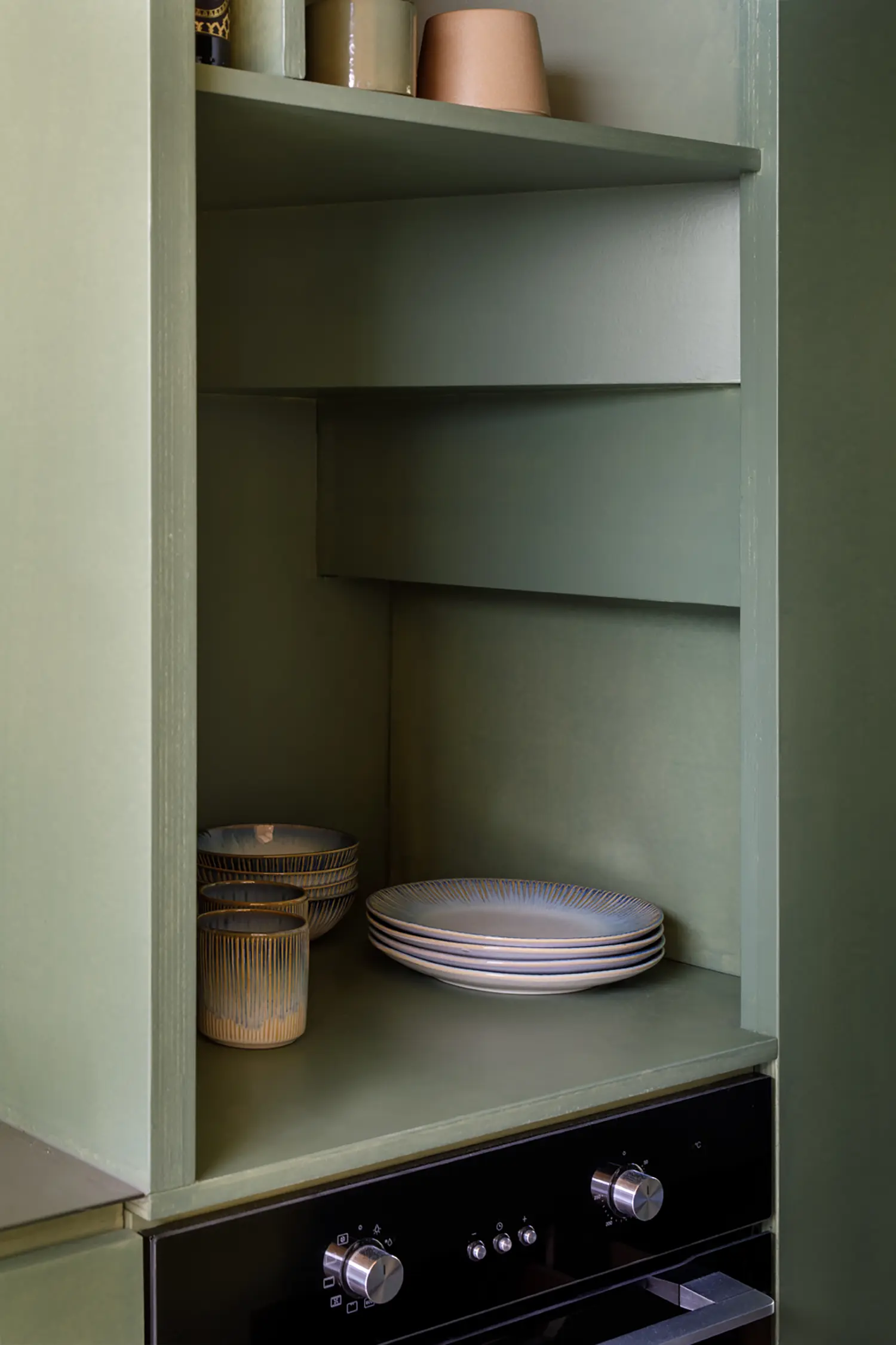 Lounge Lodge kitchen detail by i29 — built-in shelving, black oven, ceramic plates and cups