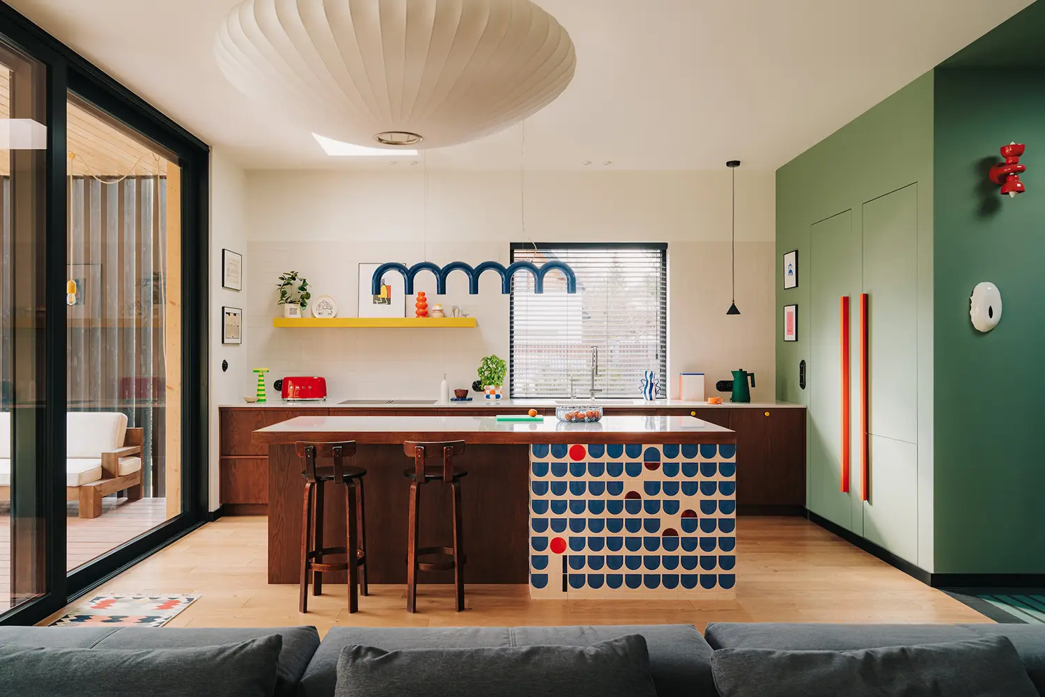 Hornówek House kitchen by one desk, near Warsaw — dark wood island with patterned tile, green wall backdrop